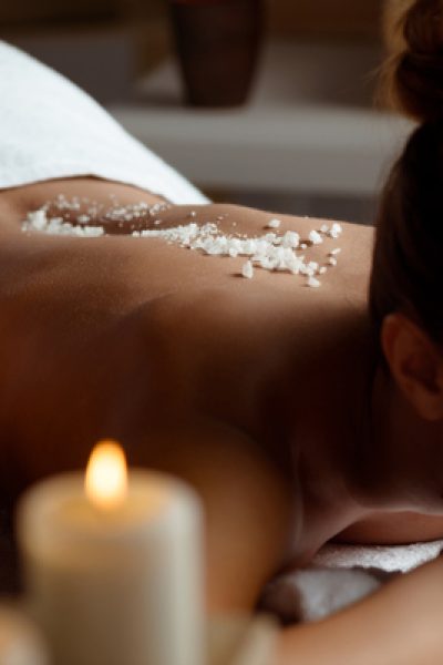 Young beautiful brunette girl relaxing in spa salon. Eyes closed. Copy space.