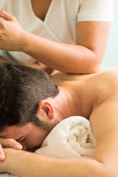 Profile view of a young man getting a lomi lomi massage in a spa clinic