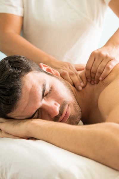 Very relaxed young Latin man getting a deep tissue massage on his back in a wellness and spa clinic